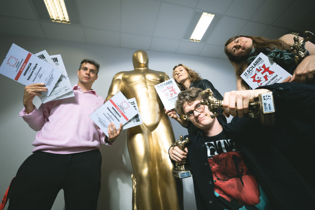Laureaci 17. Solanin Film Festival pozują do wspólnego zdjęcia ze statuetkami i dyplomami. W tle monumentalna rzeźba statuetki.